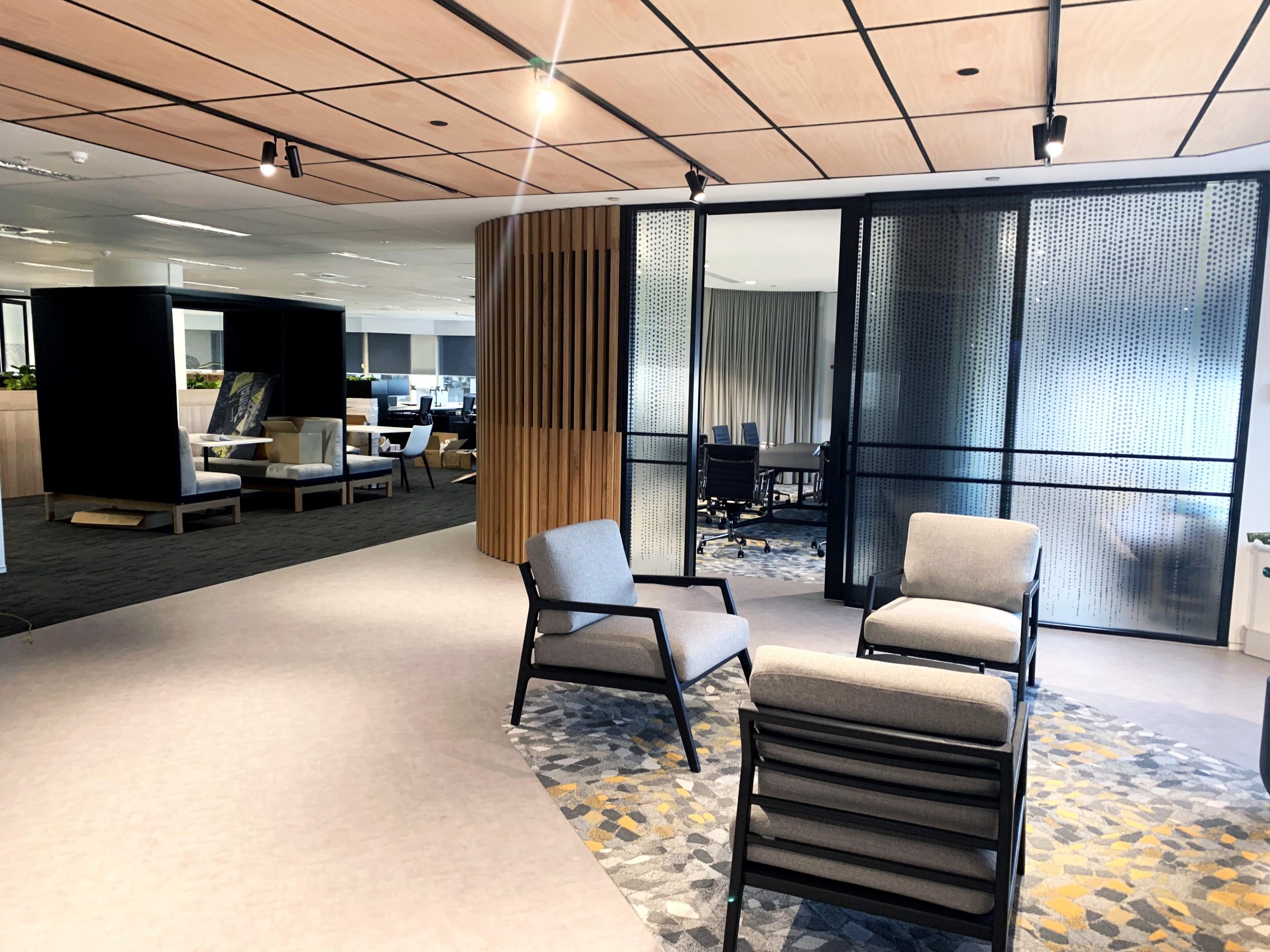 Three chairs in office reception area with glass wall beyond