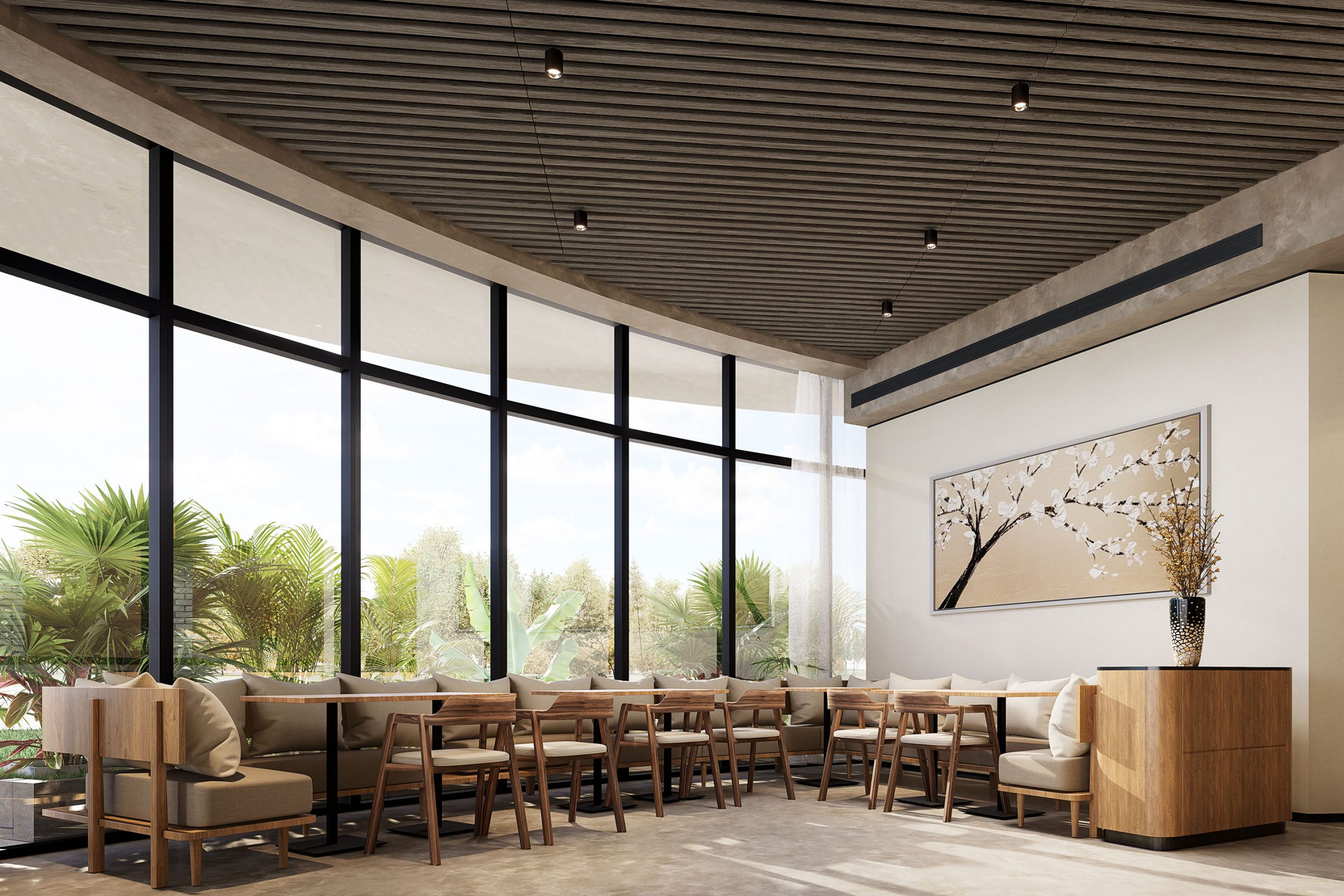 A modern, bright cafe with floor-to-ceiling windows, light wooden chairs, and cushioned bench seating. The ceiling features slats and recessed lighting within an acoustic felt ceiling frame. A large piece of wall art depicting a tree branch with flowers is displayed on the wall.