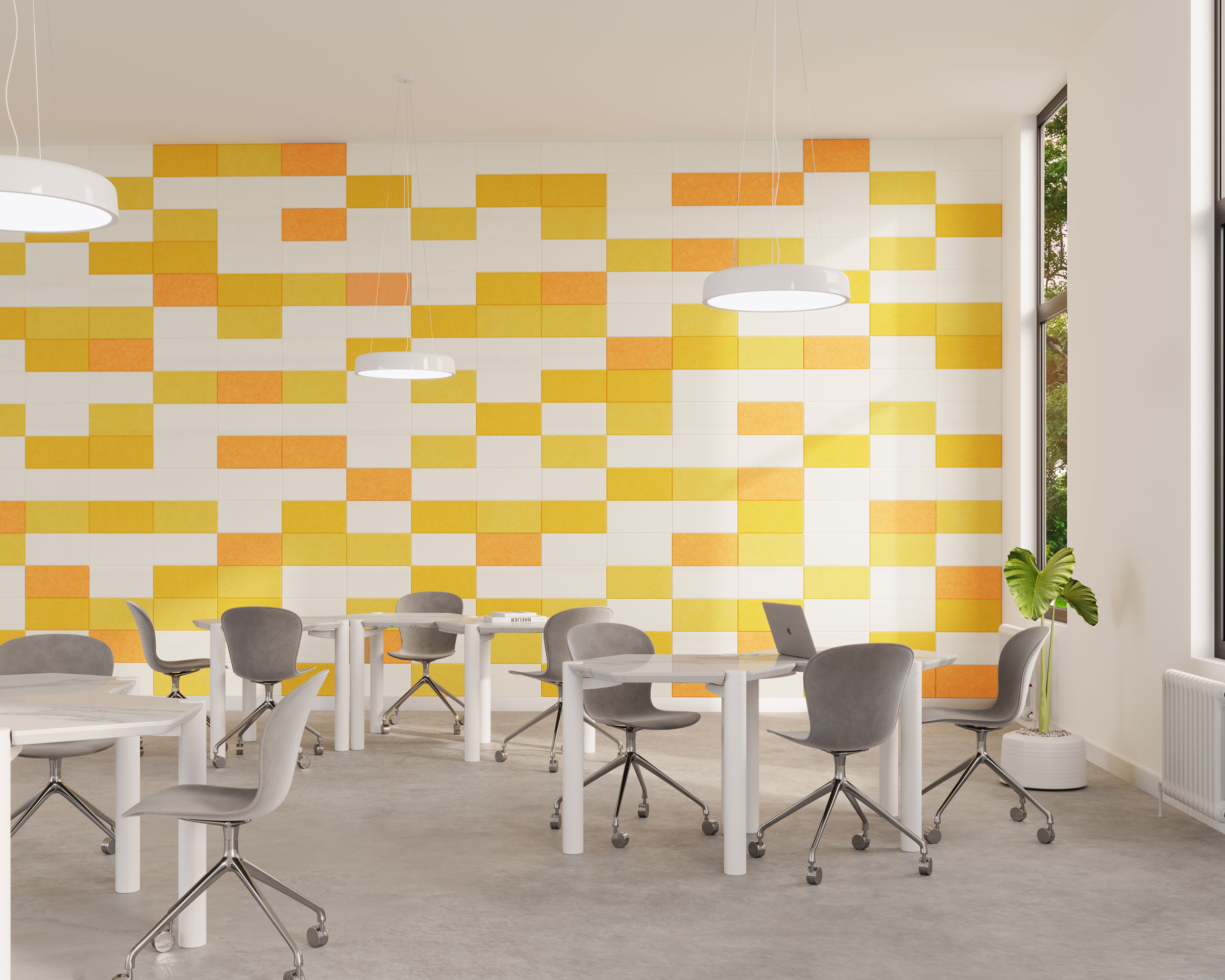 A modern office space with white desks and gray chairs arranged in an open layout. The back wall features a vibrant, geometric pattern in shades of yellow and white made from acoustic felt wall tiles. Pendant lights hang from the ceiling, and a potted plant is placed near a large window on the right.