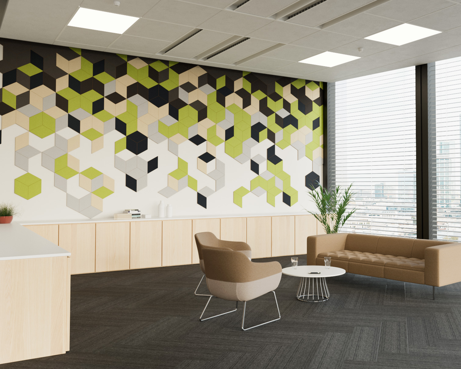 Modern office lounge with geometric wall art featuring green, black, and beige diamond patterns made from acoustic felt wall tiles. The room has a sofa, two chairs, a small round table, and a potted plant near large windows with blinds. Light wood paneling and neutral tones create a serene atmosphere.