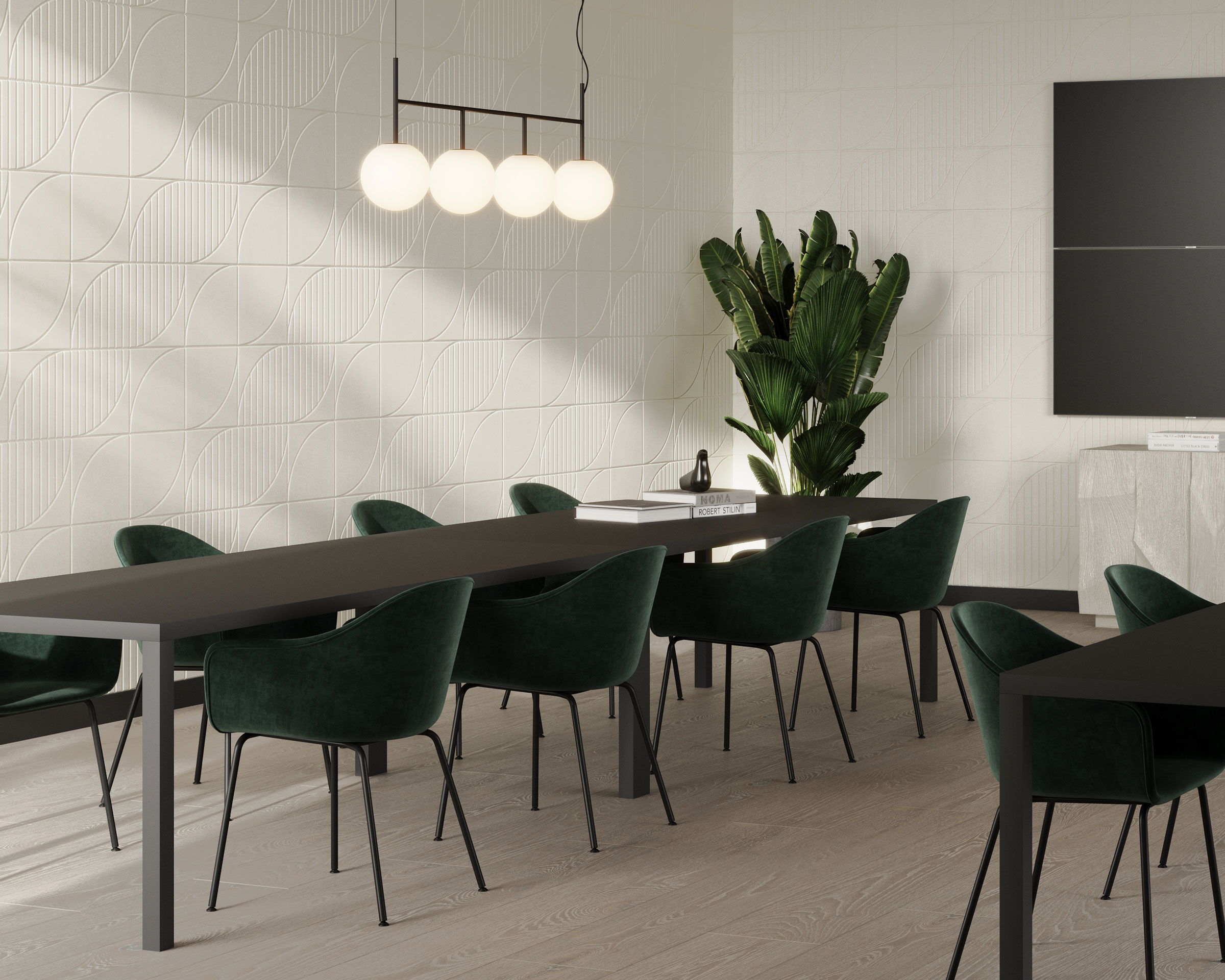 Modern dining room with a long dark table and green velvet chairs. A cluster of spherical pendant lights hangs above the table. A potted plant stands in the corner, and textured white walls with acoustic felt wall tiles complement the room’s minimalist design.