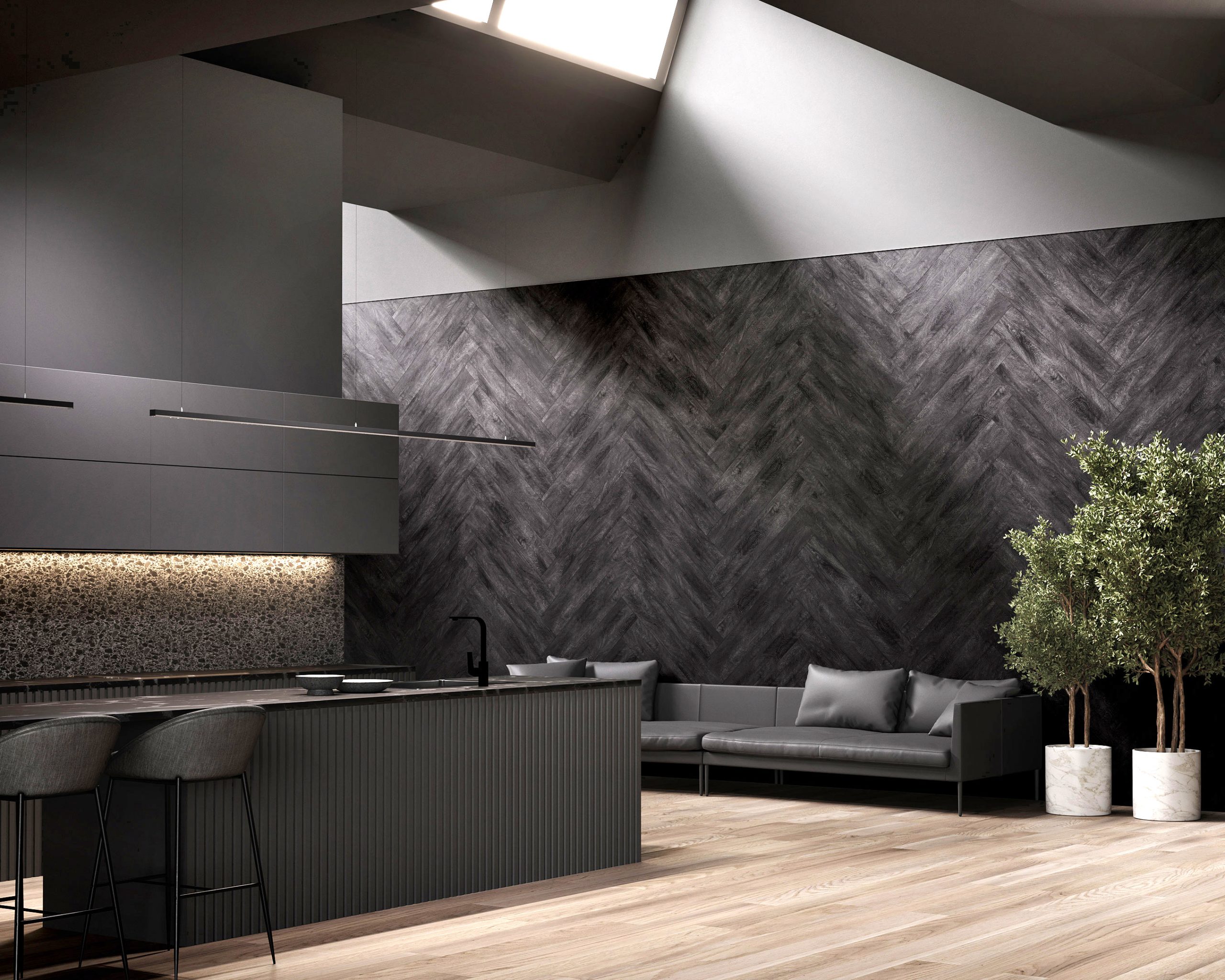 A modern, minimalist kitchen and living area features dark cabinetry and acoustic felt wall planks in a herringbone pattern. The space includes a sleek island with barstools, a low sofa, light wooden flooring, and potted plants, all under a skylight.