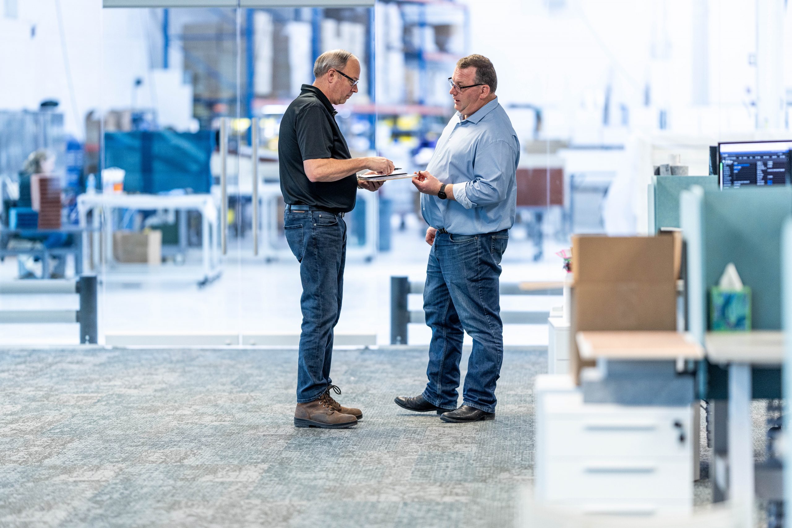 Two men talking on the Acoufelt factory floor.