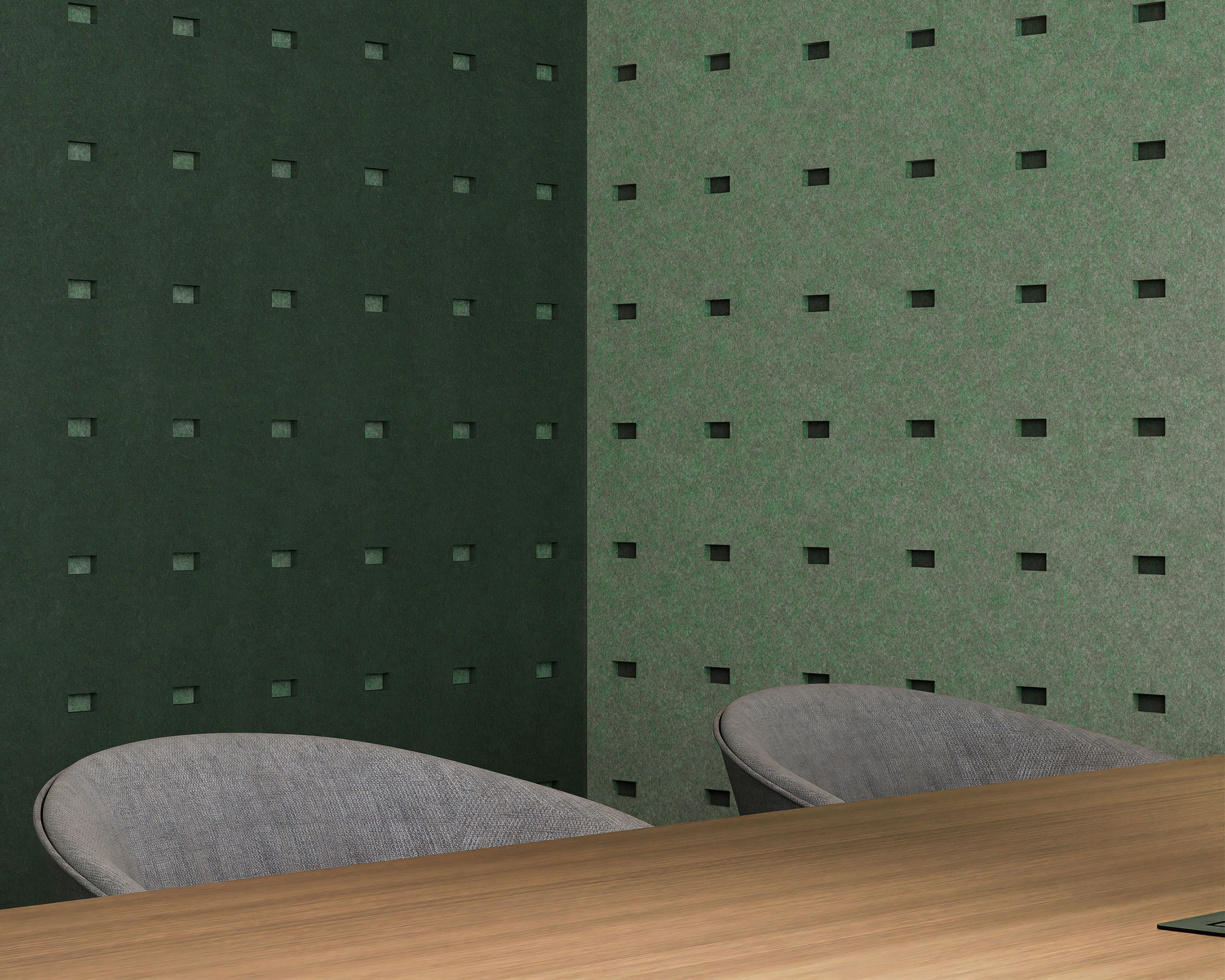 A modern office corner with dark green and light green walls featuring small rectangle cutouts in the acoustic felt wall panels. The room contains a wooden desk and two gray fabric chairs, with the minimalist design focusing on clean lines and a calming color palette.
