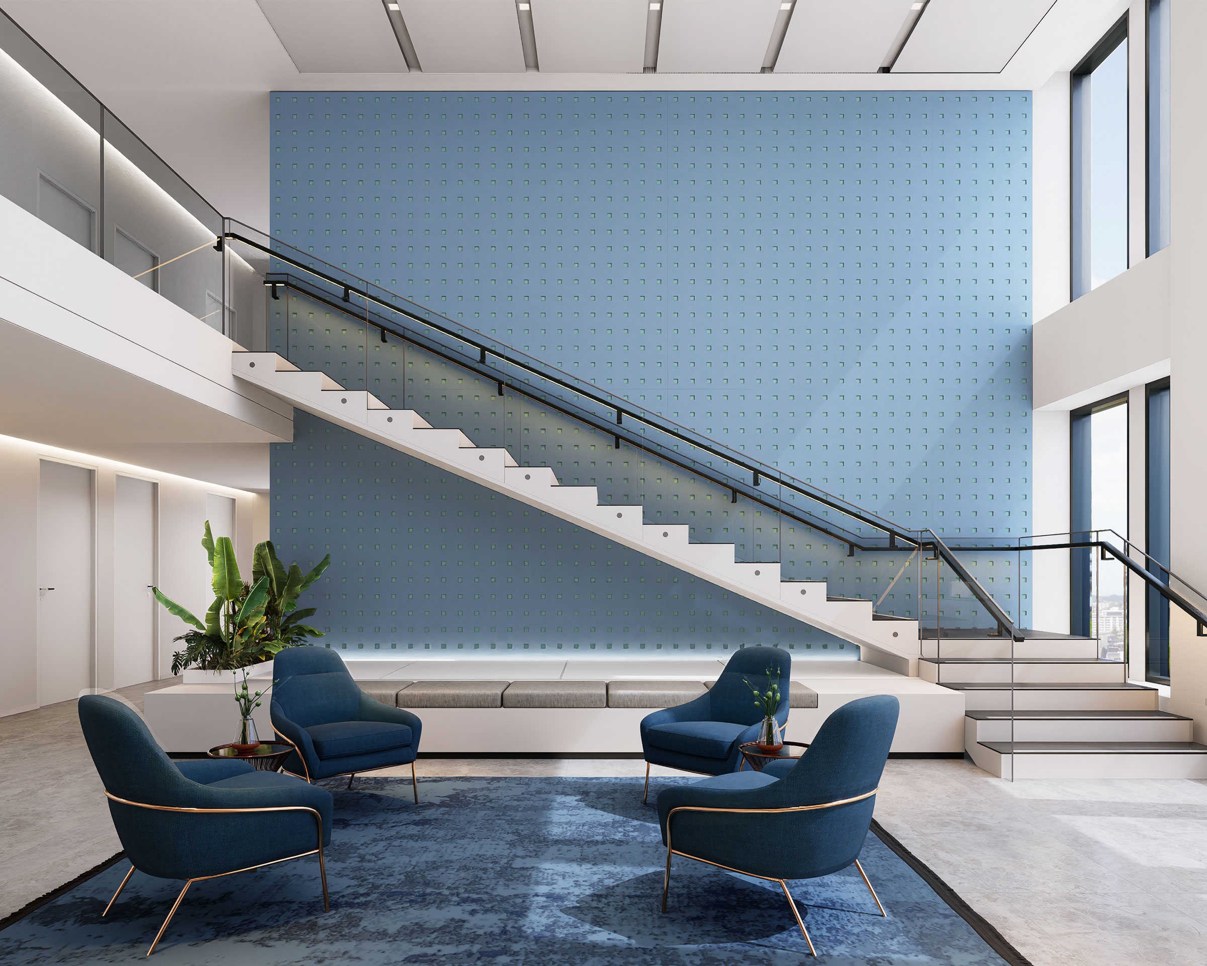 A modern, spacious lobby featuring a wide staircase with black railings, set against a large blue acoustic felt wall. The area boasts stylish blue armchairs arranged around a rectangular rug, lush potted plants, large windows, and ample natural light.