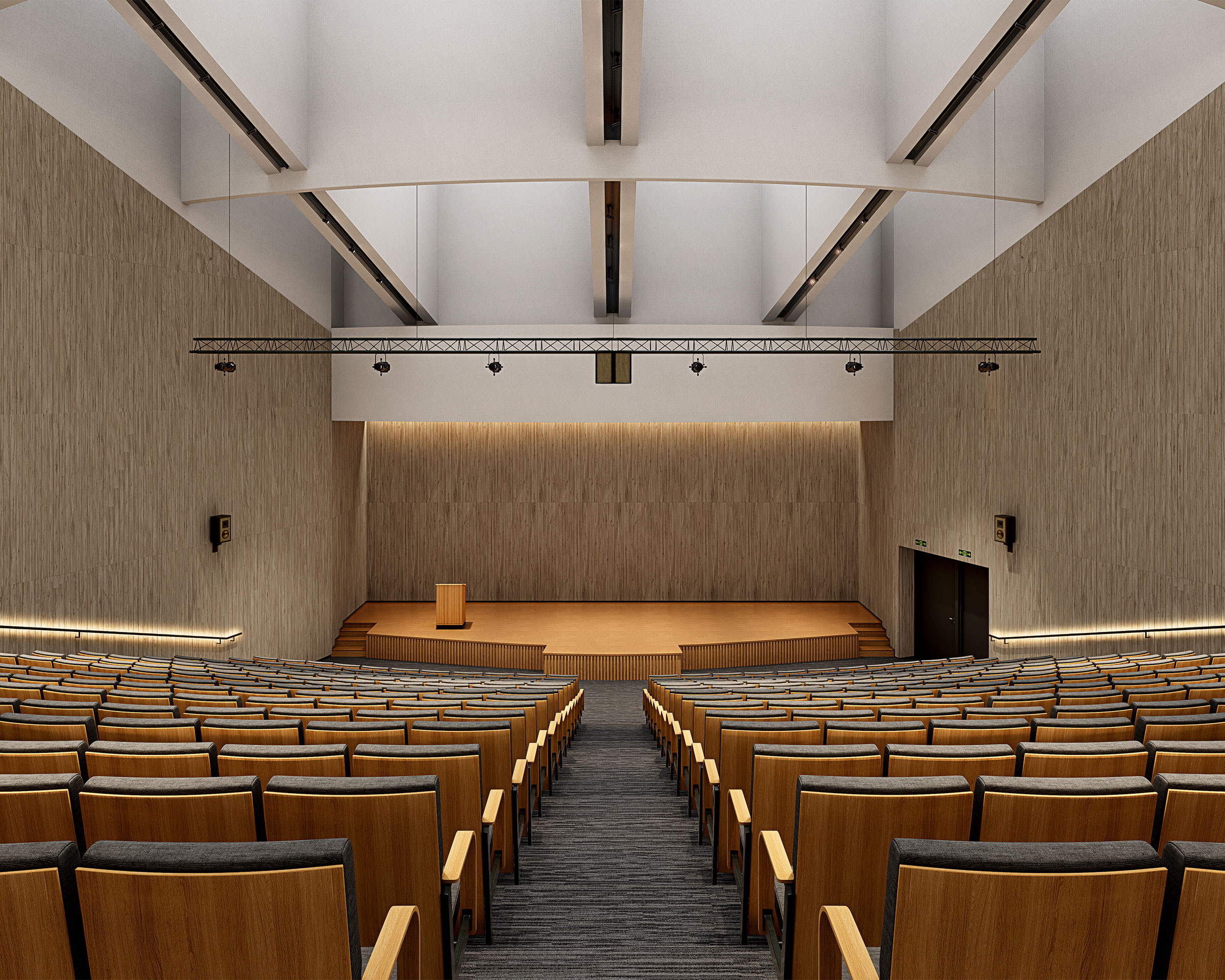 An empty auditorium with wooden seats and a modern design. It features a large stage at the front with a podium, high ceilings adorned with beams, and concealed lighting. The venue is well-lit, enhanced by woodgrain acoustic felt slats for optimal sound quality. Emergency exit doors are visible on the right side near the stage.
