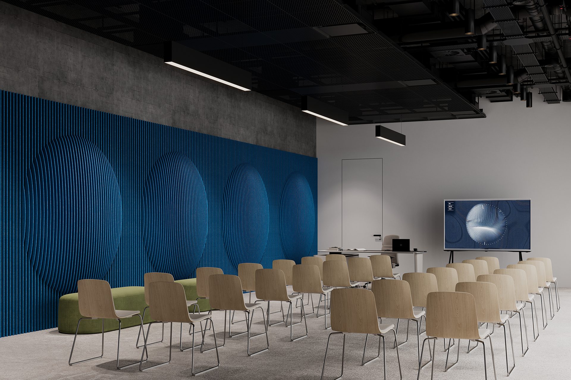 A modern conference room with rows of beige chairs facing a large screen on the right. The room features a blue textured wall with circular patterns, a green bench, and a ceiling with exposed pipes and suspended lights. A door is visible at the back.