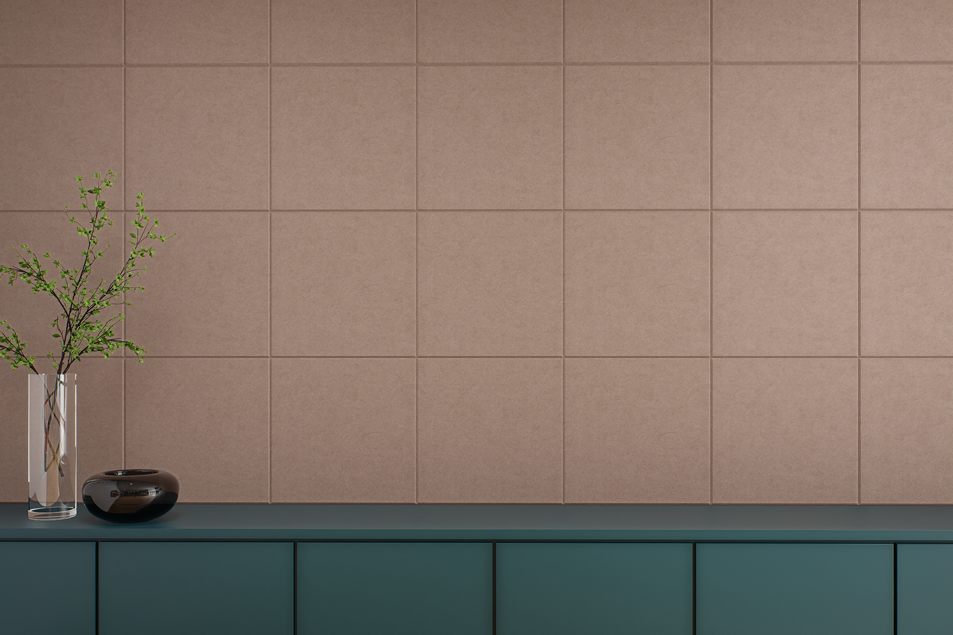 A minimalist interior features a teal cabinet against a beige-pink acoustic felt tiled wall. On the cabinet are a transparent vase holding green branches and a small, dark-colored ceramic bowl. The scene exudes simplicity and modern elegance.