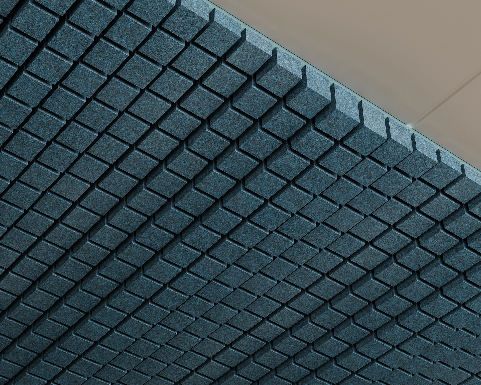 Close-up view of a ceiling with a geometric, three-dimensional grid pattern composed of grayish-blue acoustic felt tiles, designed to create a textured and industrial aesthetic. The recessed tiles create a visual effect of depth and shadow. The ceiling is angled diagonally in the frame.