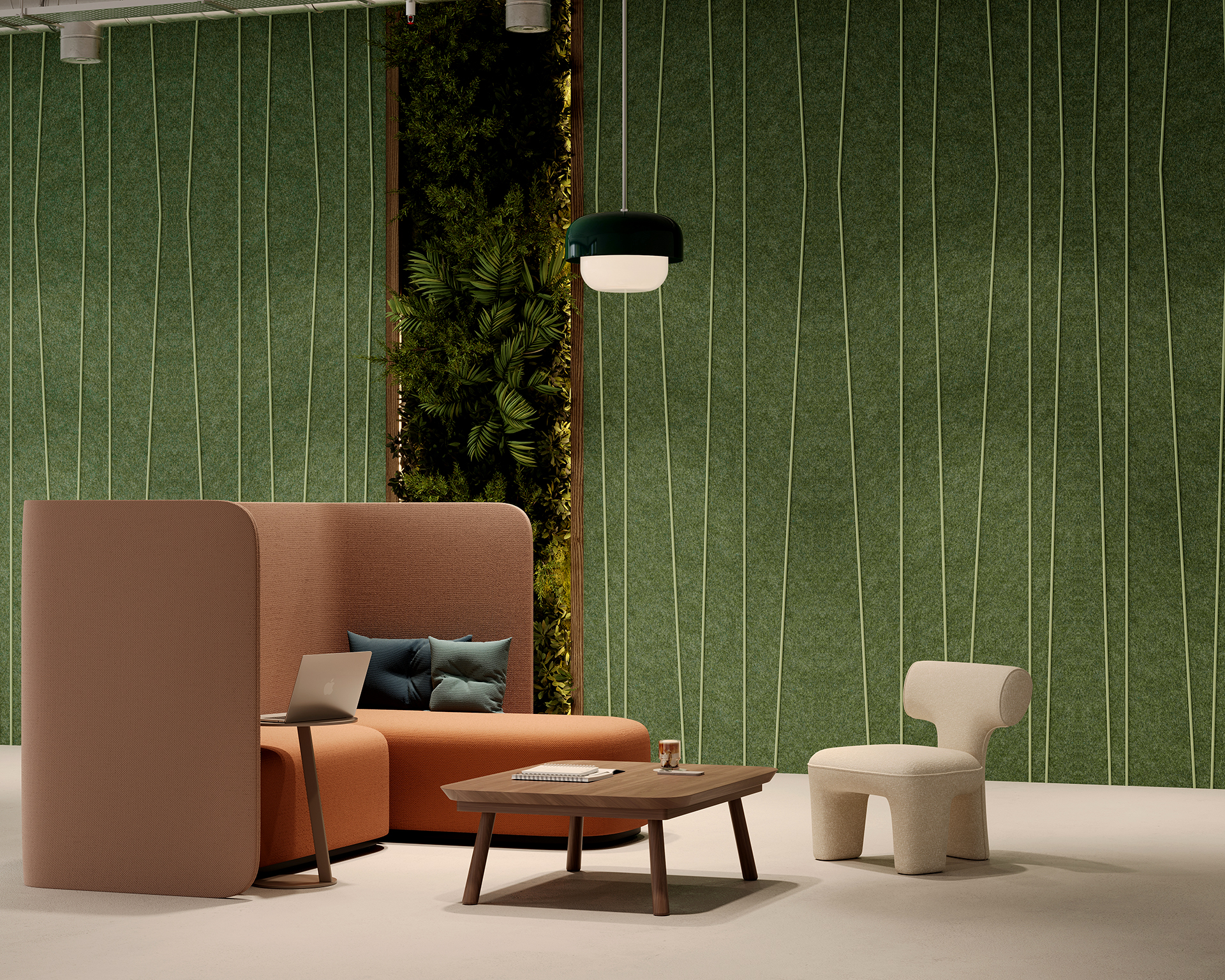 A modern lounge area with a curved sofa and several cushions, a small wooden coffee table, and a white chair. A laptop is on the sofa. The background features a green acoustic felt wall with plant accents and a hanging light fixture.