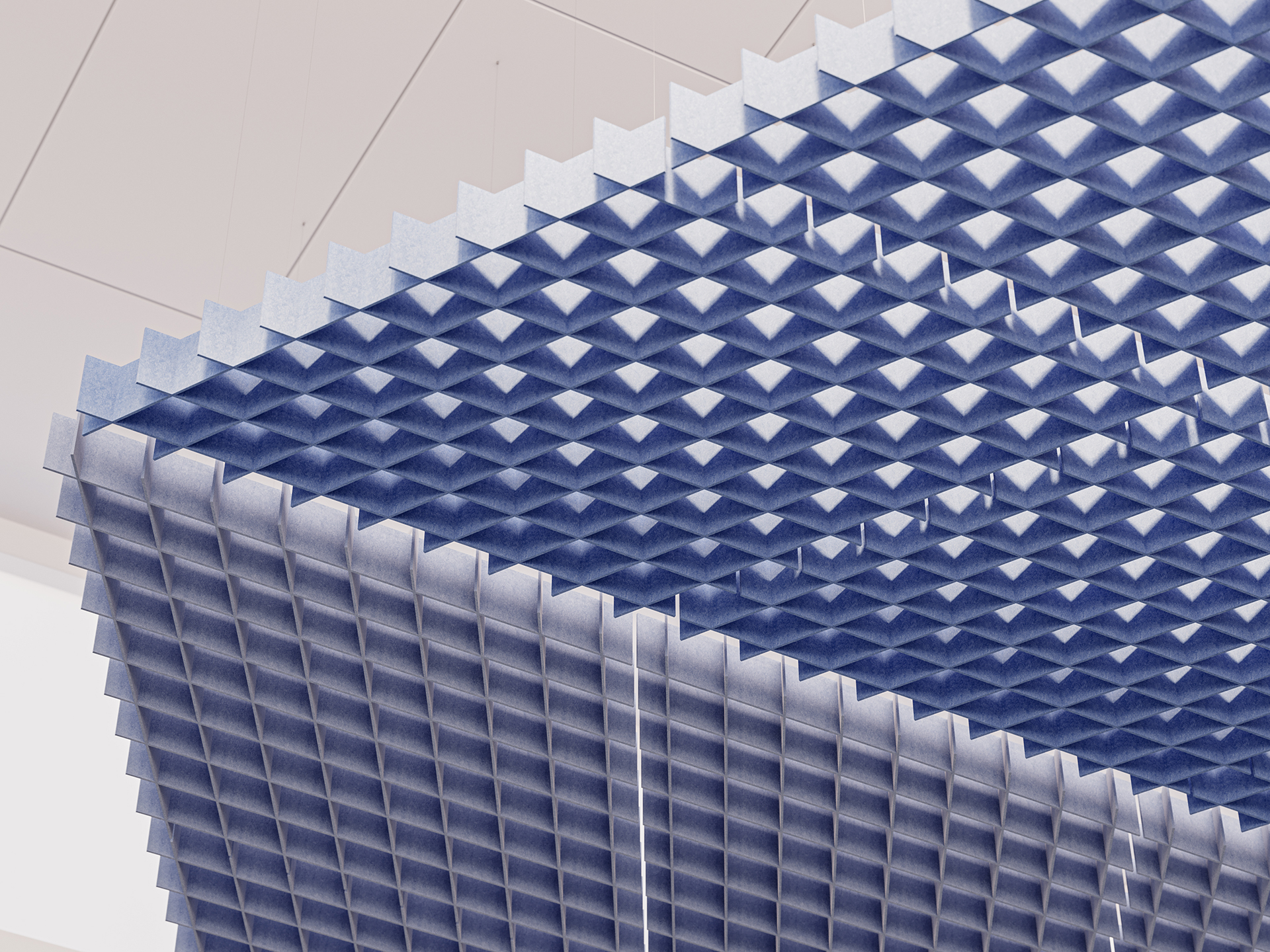 A close-up view of a suspended, blue, grid-patterned acoustic ceiling cloud with a geometric, three-dimensional texture, hanging from a white ceiling.