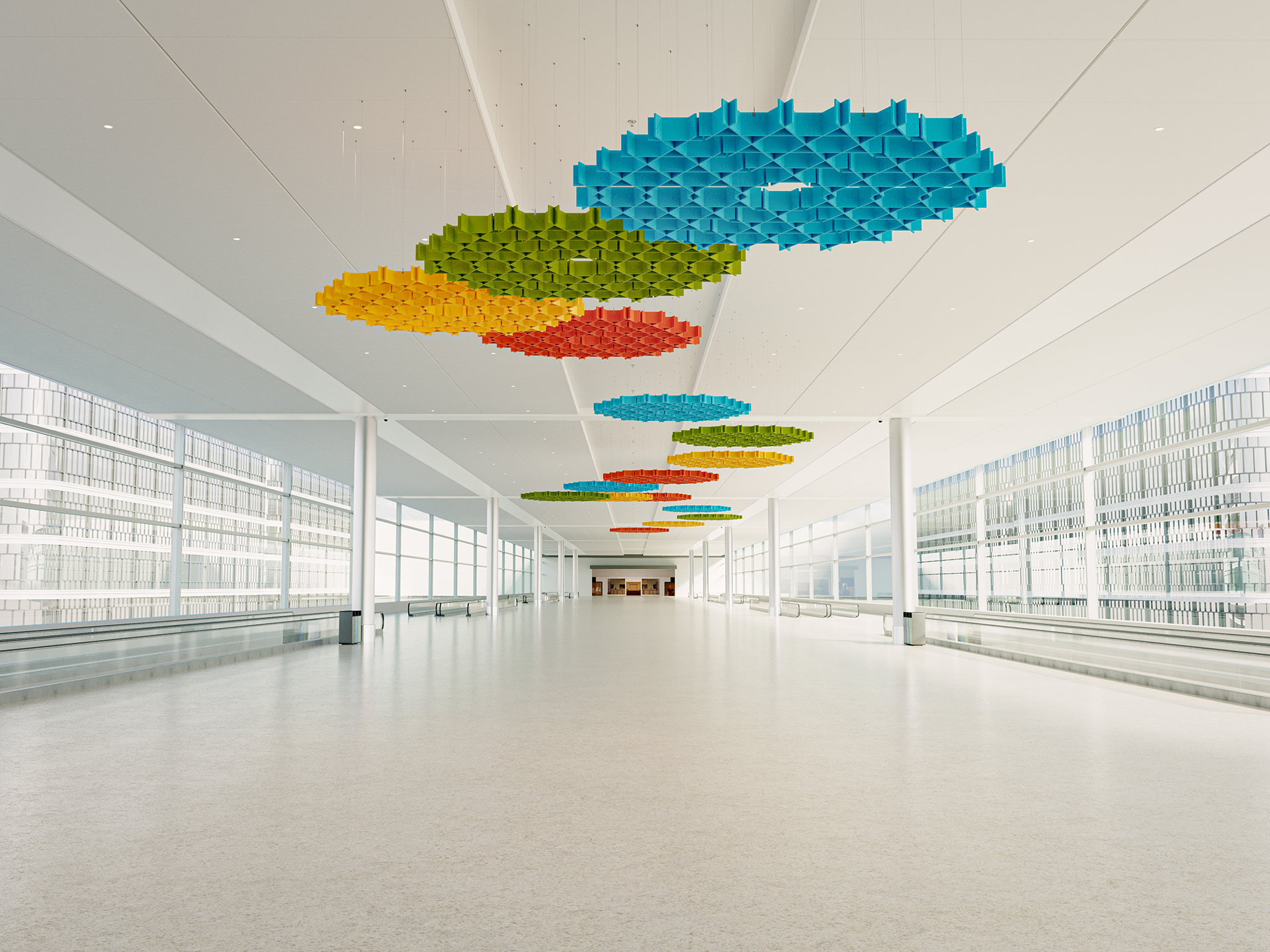 A bright, spacious corridor with floor-to-ceiling windows and colorful geometric acoustic felt ceiling art in blue, green, orange, and yellow. The space looks modern and minimalistic with no people present.