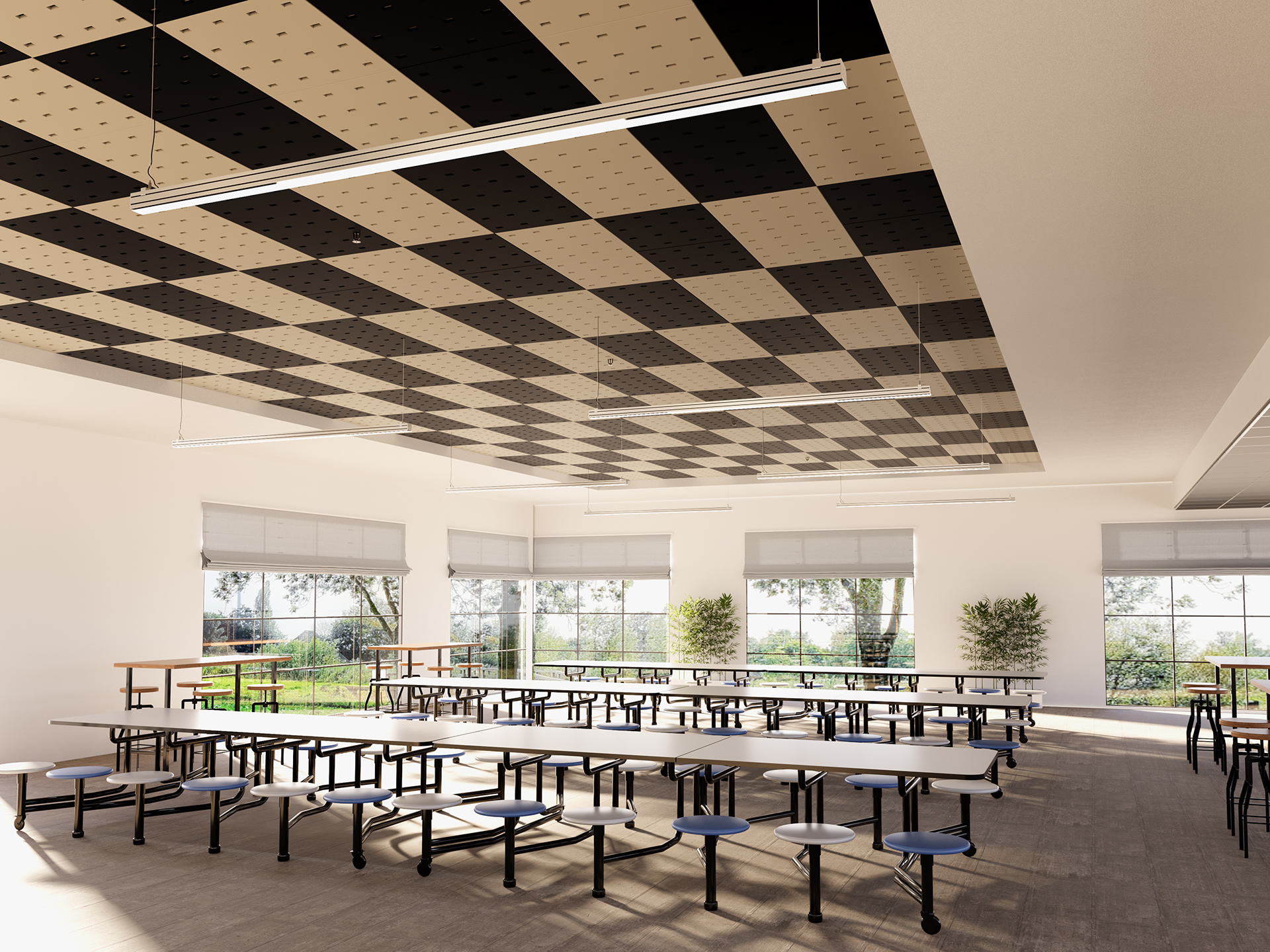 A spacious cafeteria with large windows, a checkered black and beige acoustic felt ceiling, long white tables with attached round stools, and potted plants by the windows. Natural light fills the bright, empty room.