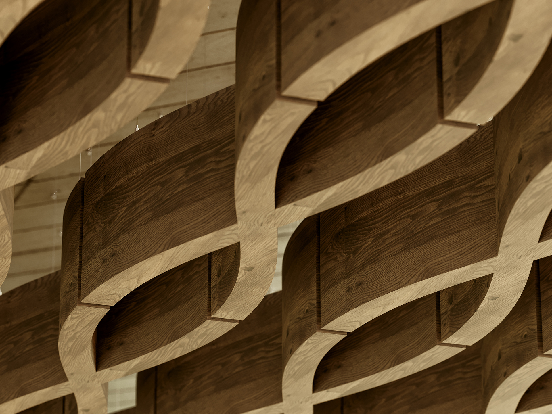 Close-up of an architectural ceiling feature with interlocking, curved woodgrain acoustic felt baffles forming a geometric, repeating pattern. The wood has a natural finish and the bafflesare suspended from the ceiling.