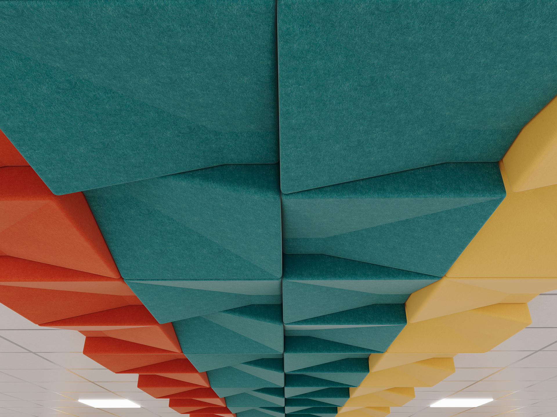 Colorful geometric acoustic felt tiles in red, teal, and yellow are arranged in rows on a ceiling, creating a modern, decorative pattern above white ceiling tiles with recessed lights.