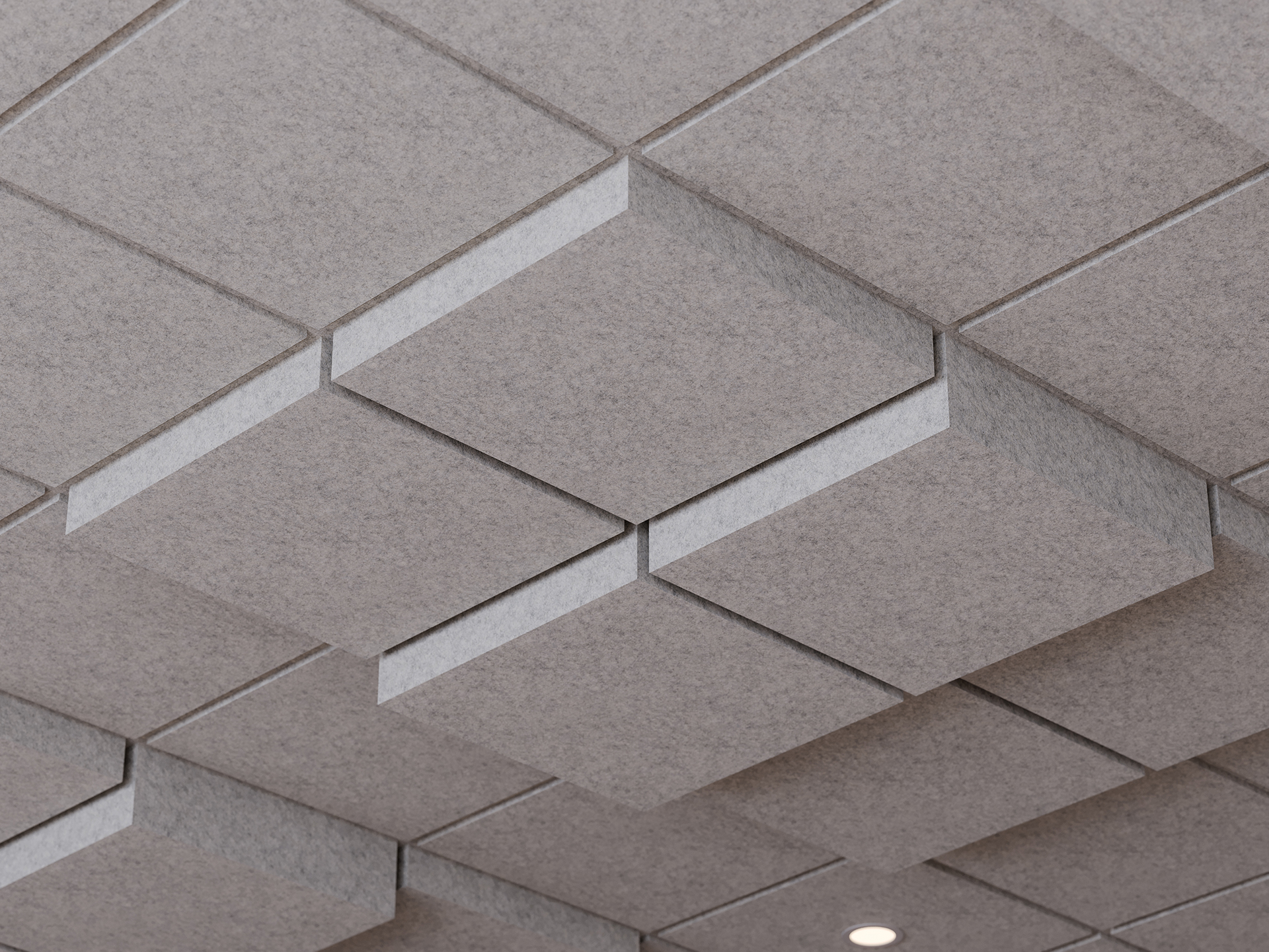 Acoustic felt ceiling with a geometric pattern of gray, textured, three-dimensional square and rectangular acoustic panels; one small round recessed light is visible in the lower right corner.