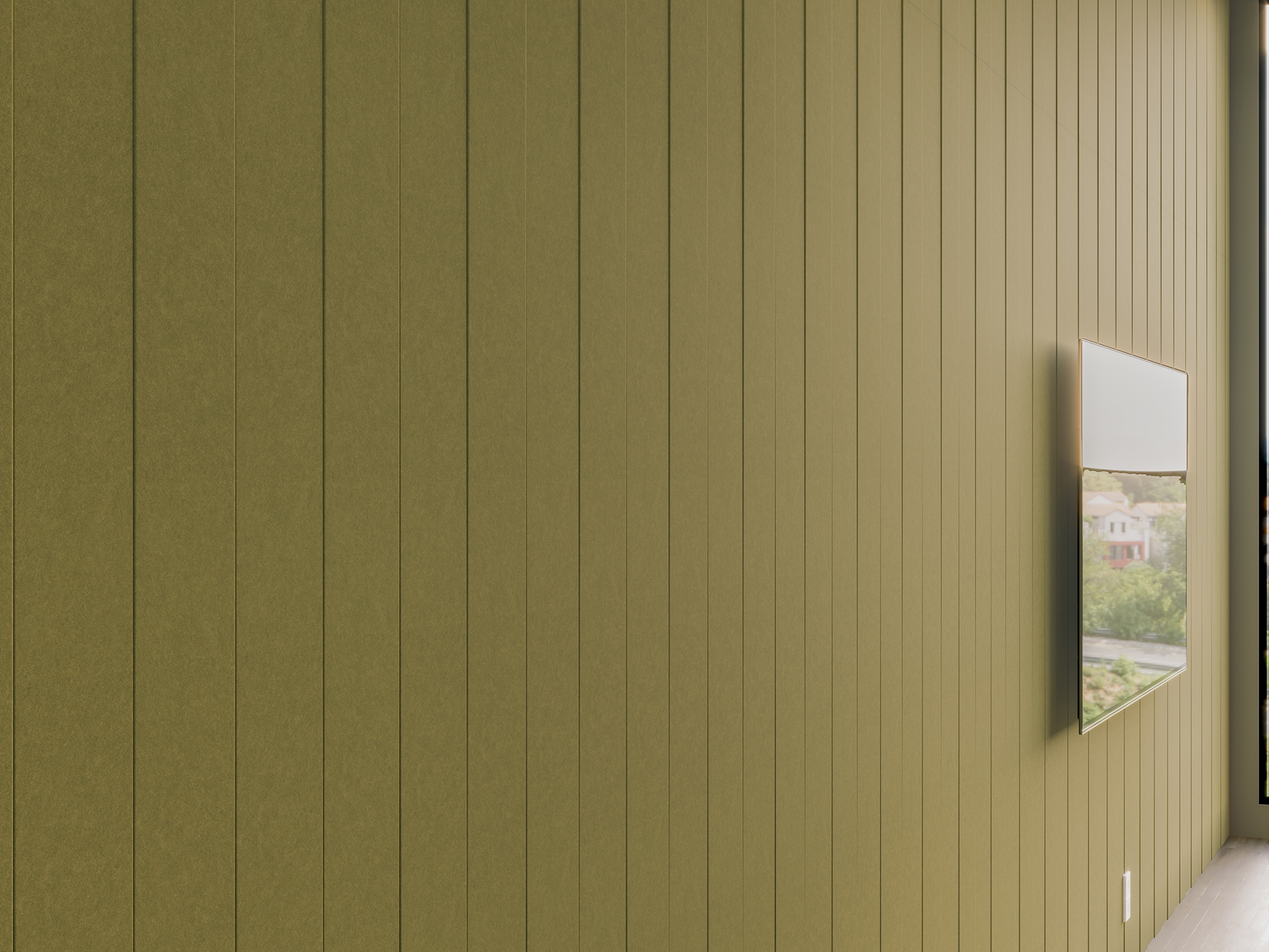 A green acoustic felt paneled wall with a flat-screen TV mounted on it, showing a landscape scene. Light enters from the right, partially illuminating the wall and floor.
